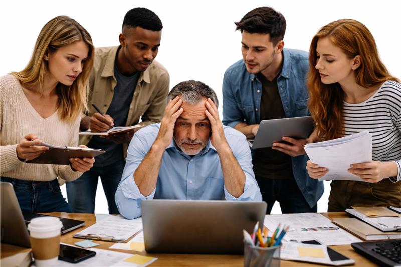 Team members crowding a stressed lead—adding people increases coordination overhead before benefits appear